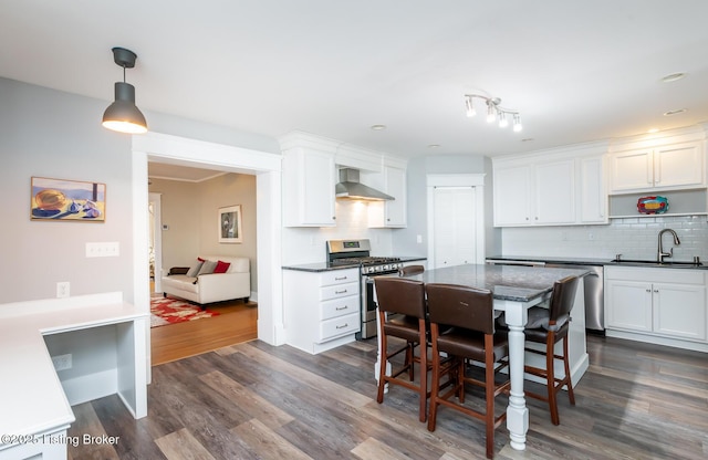 kitchen with stainless steel appliances, white cabinetry, sink, and wall chimney range hood