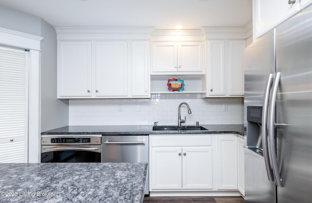 kitchen featuring white cabinetry, sink, dark stone countertops, decorative backsplash, and stainless steel appliances