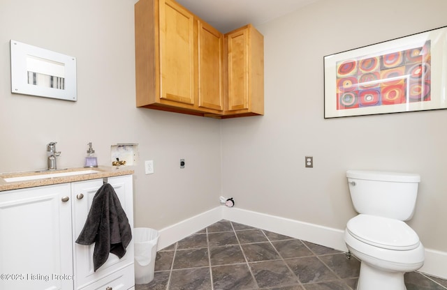 clothes washing area with sink, hookup for an electric dryer, and dark tile patterned flooring