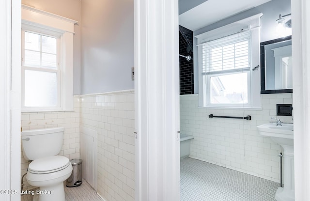 bathroom with tile patterned flooring, a wealth of natural light, tile walls, and toilet