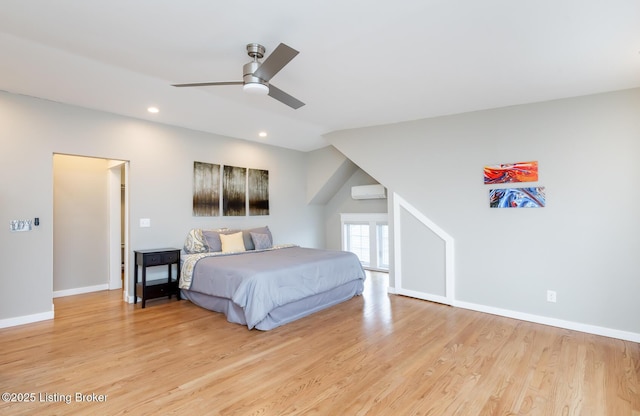 bedroom with ceiling fan, a wall unit AC, and light hardwood / wood-style floors