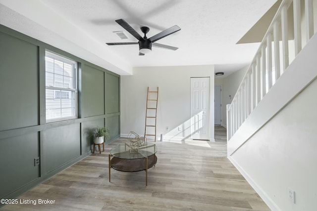 living area featuring ceiling fan, a textured ceiling, and light hardwood / wood-style flooring