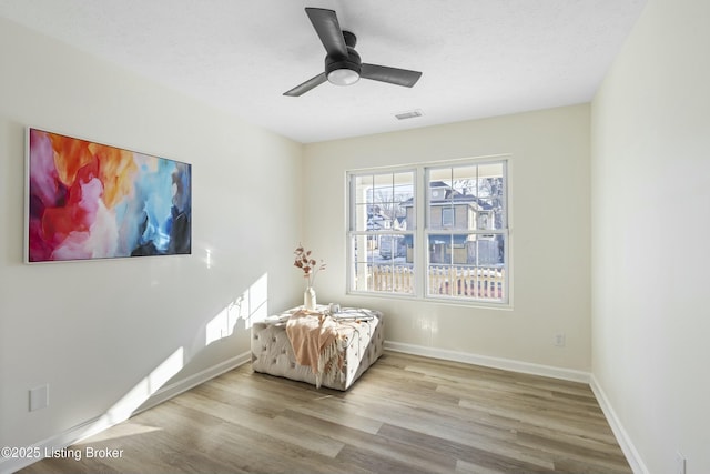 living area featuring a textured ceiling, ceiling fan, and light hardwood / wood-style flooring