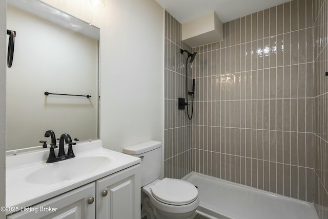 bathroom with vanity, tiled shower, and toilet