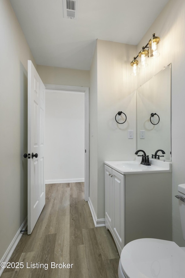 bathroom with hardwood / wood-style flooring, vanity, and toilet