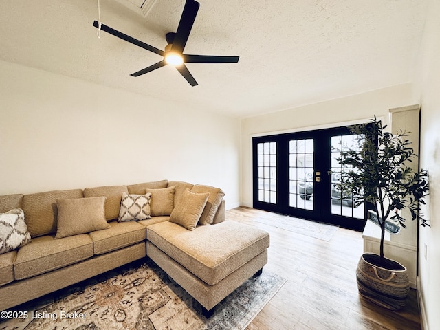 living room featuring french doors, ceiling fan, hardwood / wood-style floors, and a textured ceiling