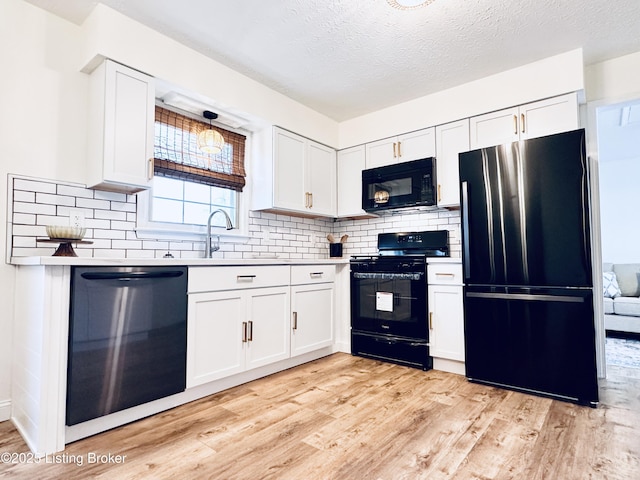 kitchen featuring sink, white cabinets, light hardwood / wood-style floors, and black appliances