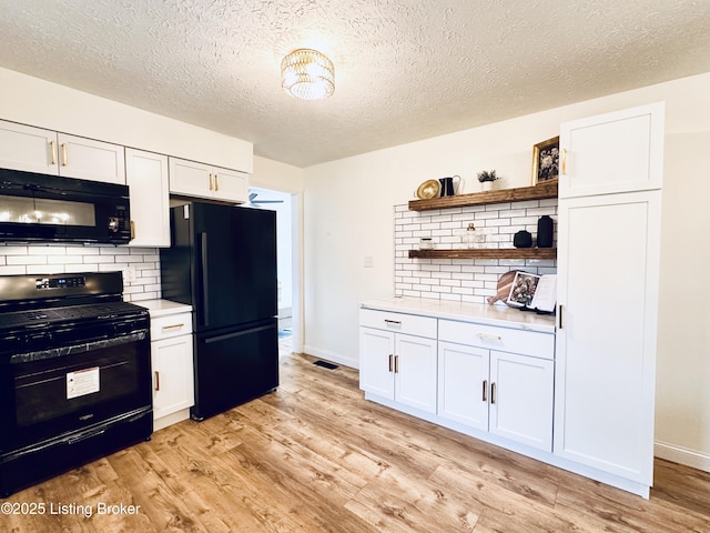 kitchen featuring tasteful backsplash, white cabinetry, light hardwood / wood-style flooring, and black appliances