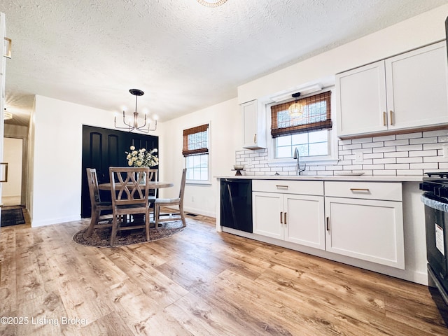 kitchen with pendant lighting, dishwasher, white cabinets, and light wood-type flooring