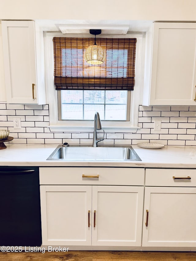 kitchen featuring sink, white cabinetry, black dishwasher, tasteful backsplash, and decorative light fixtures