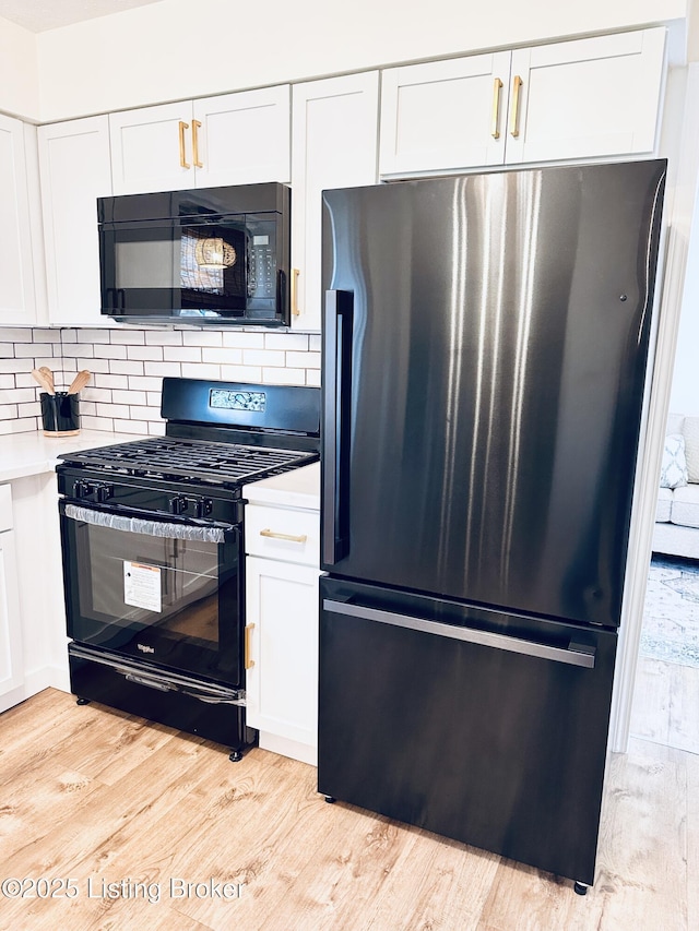 kitchen featuring white cabinetry, light hardwood / wood-style flooring, tasteful backsplash, and black appliances