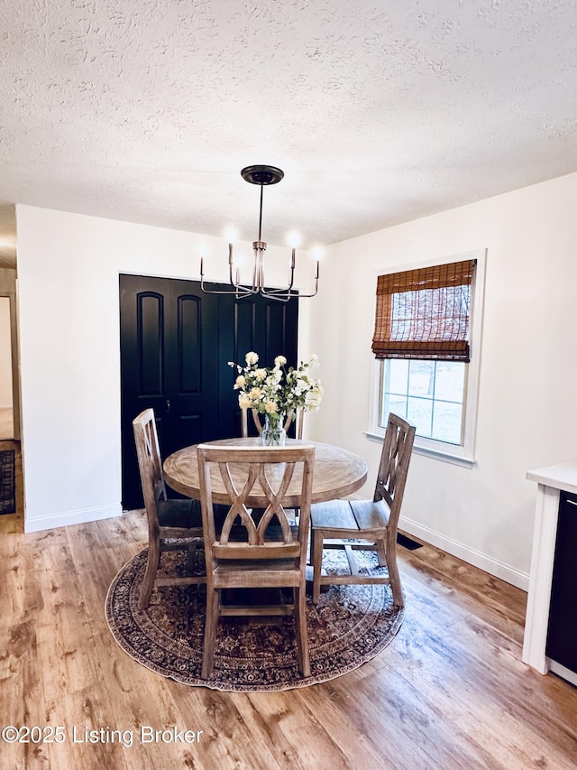 dining area featuring a textured ceiling, a chandelier, and light hardwood / wood-style flooring