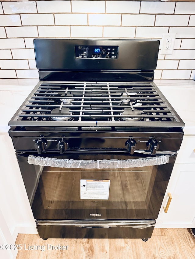 room details featuring decorative backsplash and black gas range oven