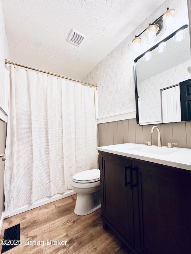 bathroom with wood-type flooring, vanity, a textured ceiling, and toilet