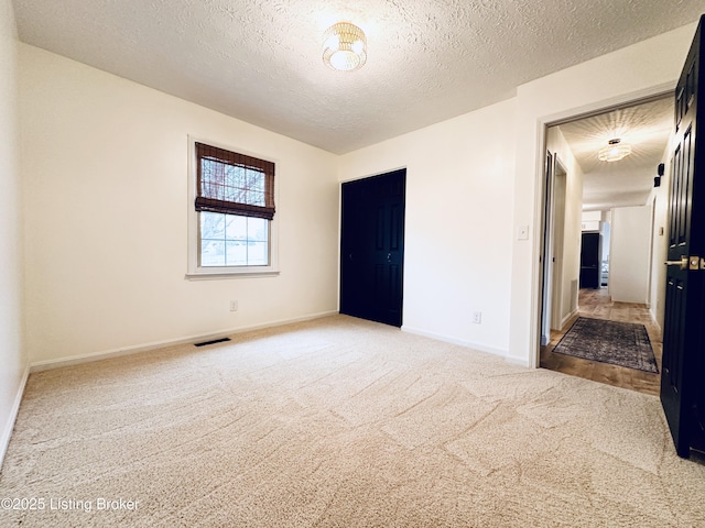 empty room featuring a textured ceiling and carpet