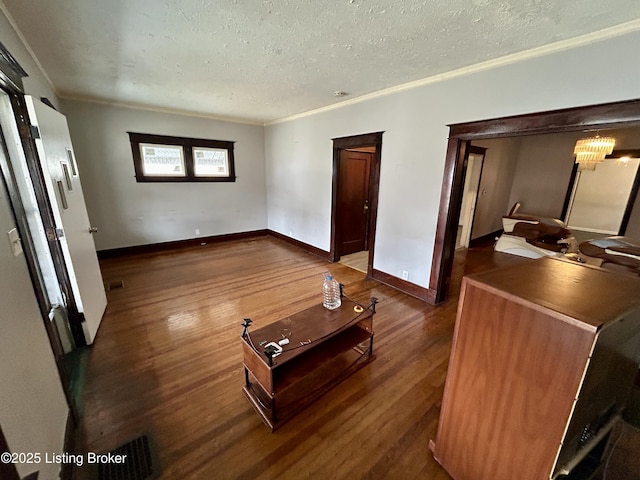 living room with dark wood-type flooring, ornamental molding, and a textured ceiling