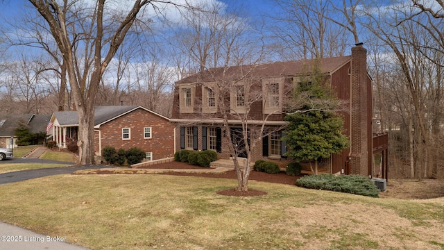 view of front of house featuring central AC, a front yard, brick siding, and a chimney