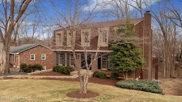 view of front facade with a front lawn, a chimney, and brick siding