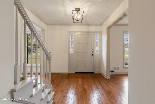 foyer featuring crown molding, stairs, visible vents, and wood finished floors