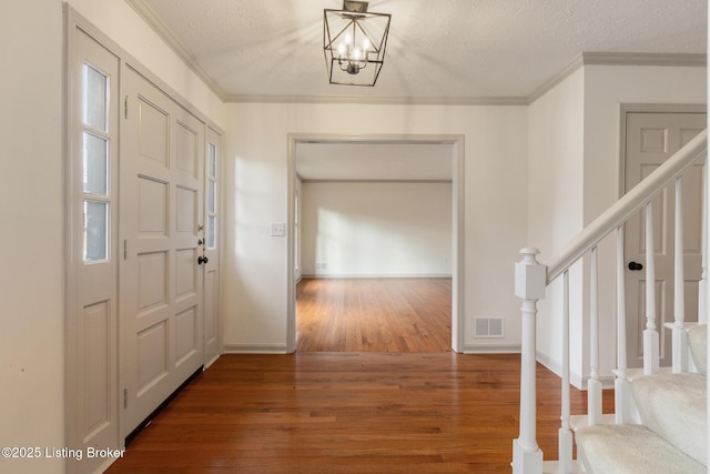 foyer entrance featuring a textured ceiling, visible vents, stairs, ornamental molding, and dark wood-style floors