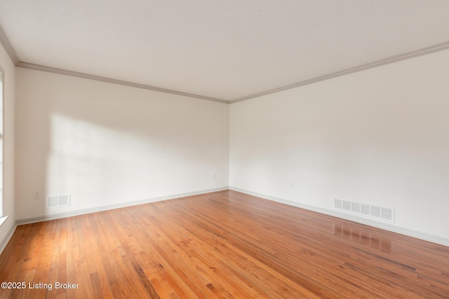 spare room with visible vents, wood finished floors, and ornamental molding