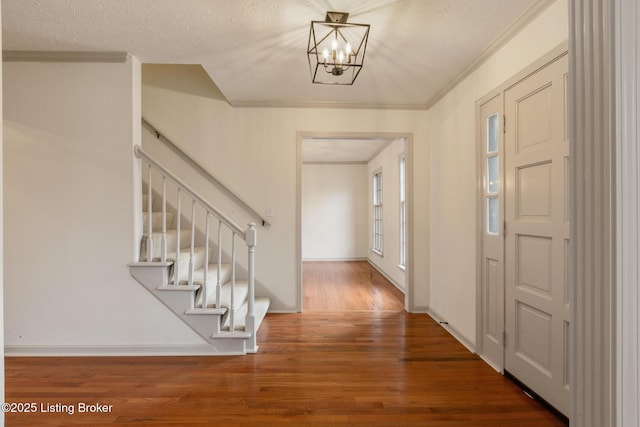 entrance foyer with crown molding, dark wood finished floors, stairway, an inviting chandelier, and a textured ceiling