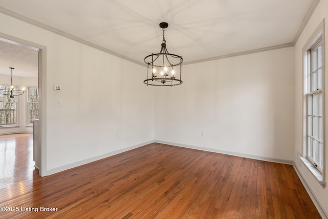 unfurnished room featuring a healthy amount of sunlight, a chandelier, crown molding, and wood finished floors