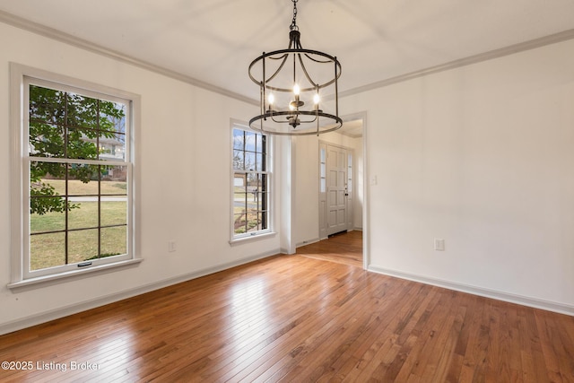 unfurnished dining area with crown molding, light wood-style floors, and an inviting chandelier