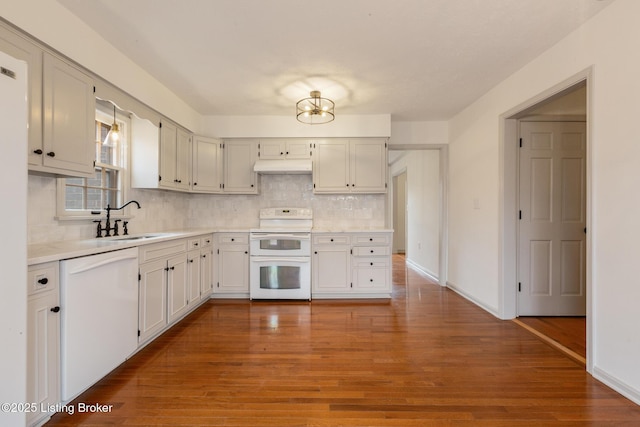 kitchen featuring under cabinet range hood, white appliances, a sink, white cabinetry, and light countertops