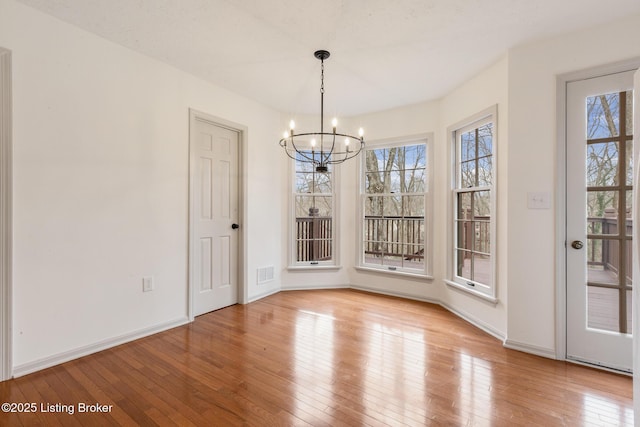 unfurnished dining area featuring a healthy amount of sunlight, visible vents, a notable chandelier, and light wood finished floors