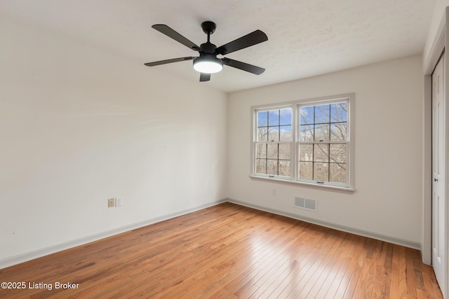 unfurnished bedroom with light wood-style flooring, a ceiling fan, visible vents, baseboards, and a closet