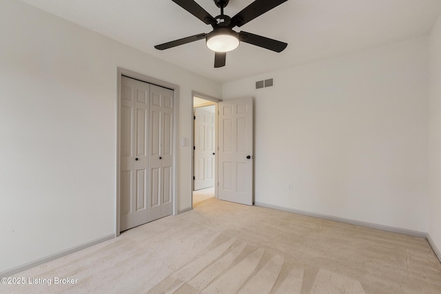 unfurnished bedroom with a closet, light colored carpet, visible vents, ceiling fan, and baseboards