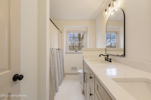 full bathroom with double vanity, a wealth of natural light, a sink, and visible vents