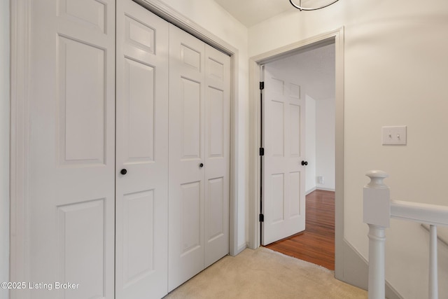 hallway with light carpet and an upstairs landing