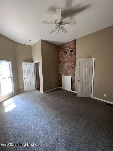 unfurnished living room featuring a ceiling fan, dark carpet, visible vents, and baseboards