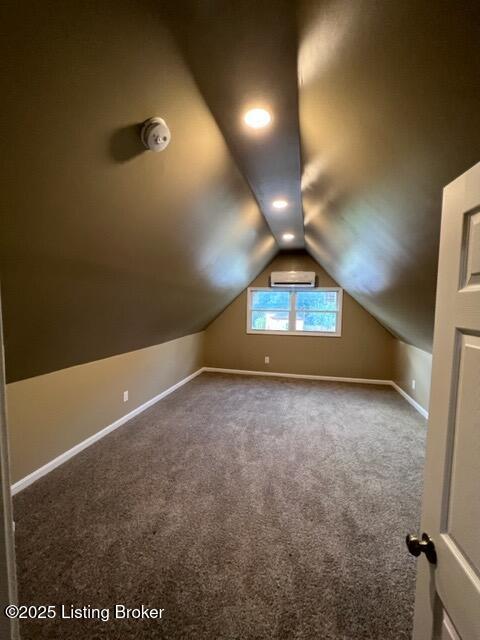 additional living space with lofted ceiling, carpet, baseboards, and a wall mounted AC