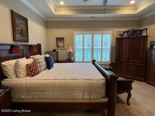 bedroom with a tray ceiling, carpet floors, and ornamental molding