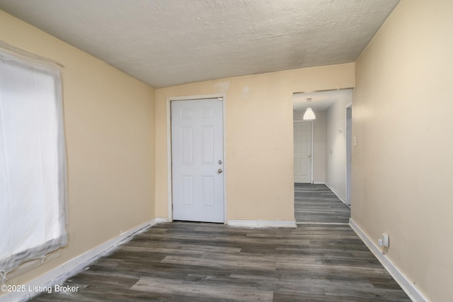 spare room featuring dark wood-type flooring and a textured ceiling