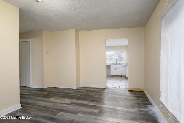 unfurnished room with dark wood-type flooring and a textured ceiling