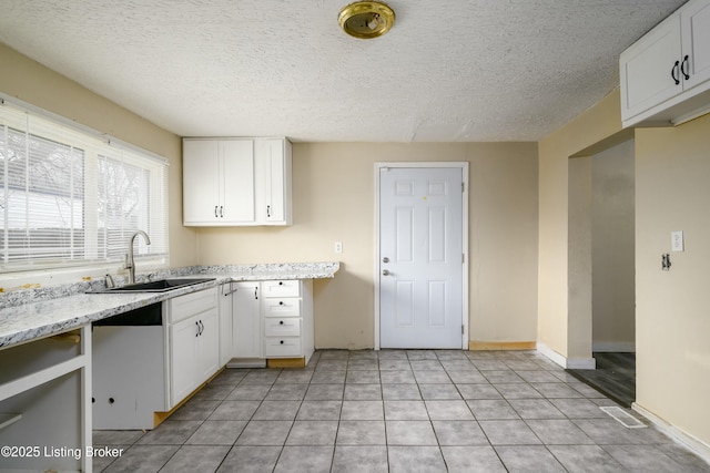 kitchen with white cabinetry, light stone countertops, sink, and light tile patterned floors