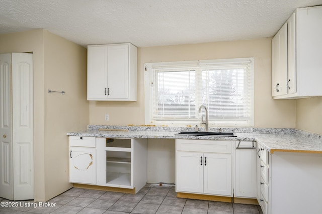 kitchen featuring white cabinetry, sink, and a textured ceiling