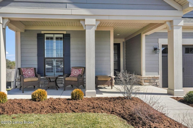 view of exterior entry with stone siding and a porch