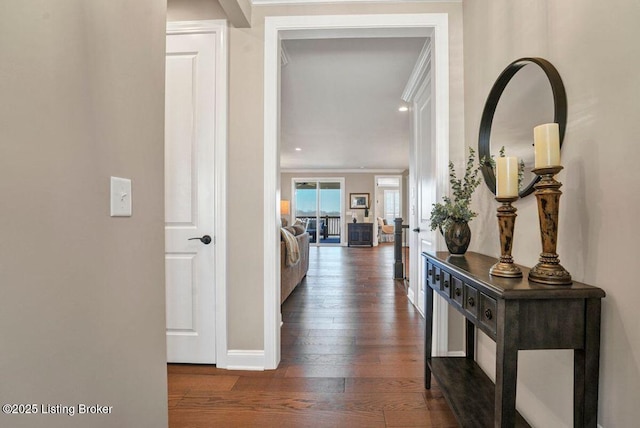 hallway with ornamental molding, baseboards, and hardwood / wood-style flooring