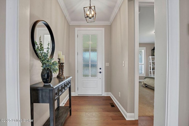 foyer entrance with visible vents, dark wood-type flooring, baseboards, ornamental molding, and an inviting chandelier