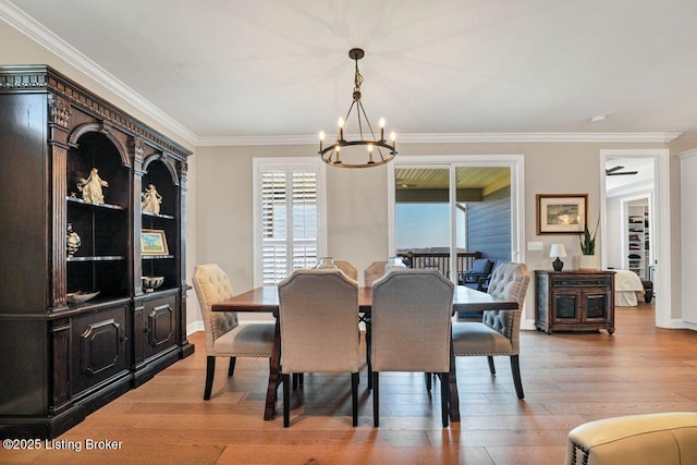 dining room with a notable chandelier, light wood-style floors, baseboards, and ornamental molding