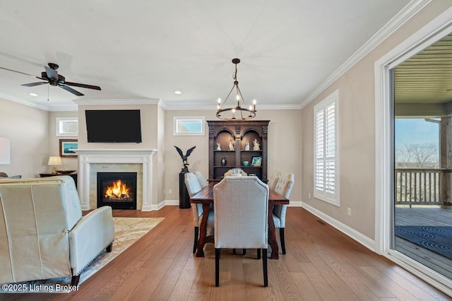 dining space featuring hardwood / wood-style floors, a fireplace with flush hearth, and baseboards