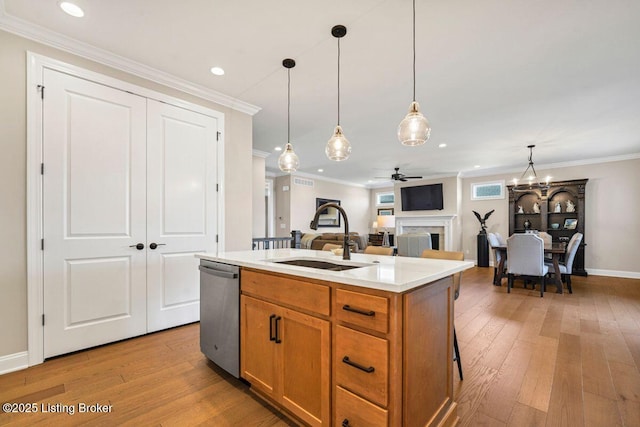 kitchen featuring ornamental molding, a sink, light wood-style floors, a fireplace, and dishwasher