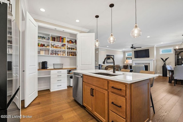 kitchen with a fireplace, a sink, built in desk, stainless steel dishwasher, and crown molding