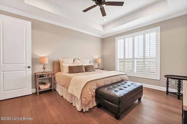 bedroom featuring a tray ceiling, baseboards, wood finished floors, and a ceiling fan