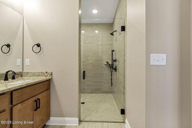 full bathroom with baseboards, a stall shower, and vanity